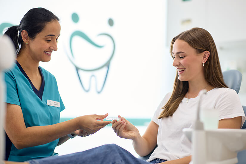 Dr. Nidhi Ramroop showing a young woman dental models